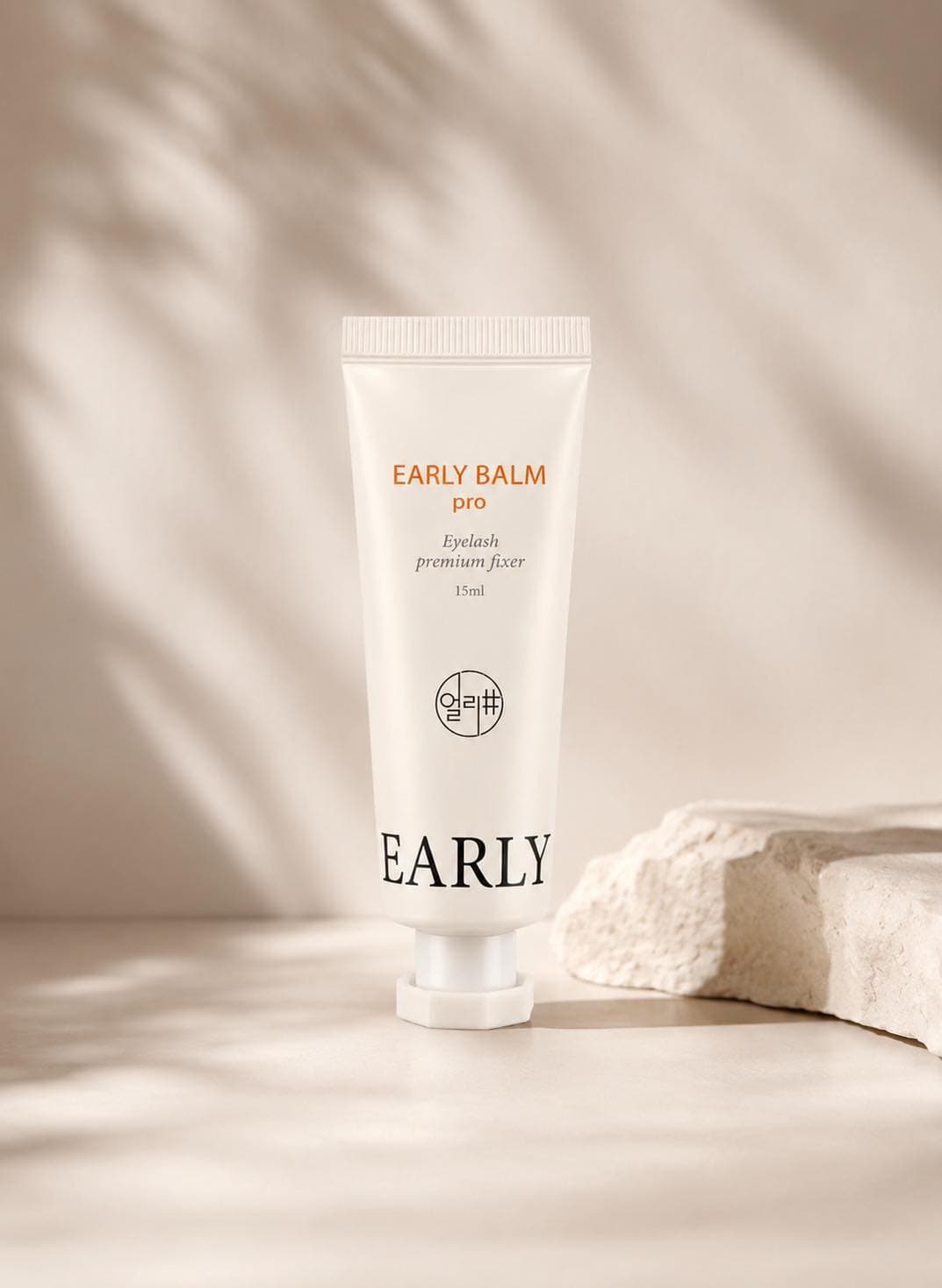 Tube of lash balm styled on a soft neutral surface